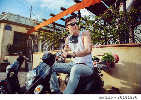 man driving vintage scooter in old town  30181830