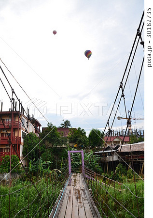 ラオスの景勝地、バンビエン 吊り橋と上空を飛行する熱気球 ラオスの景勝地、バンビエン 吊り橋と上空を飛行する熱気球 30182735