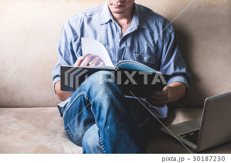 Casual young man reading documents on sofa  30187230