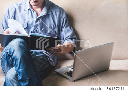 Casual young man reading documents on sofa Casual young man reading documents on sofa 30187231