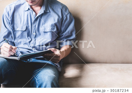 Casual young man writing some data in notebook  30187234
