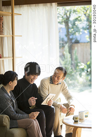 祖父母と写真を見る孫 30193040