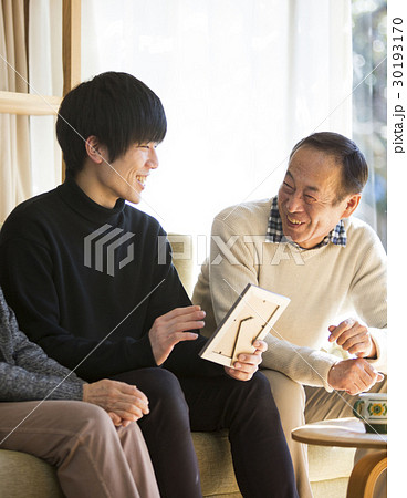 祖父母と写真を見る孫 30193170