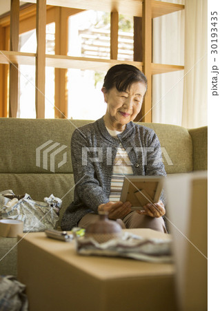 引っ越し作業　写真を見るシニア女性　 30193435