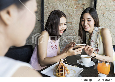 A young girl shows her photo in her smarphone to a friend 30193687