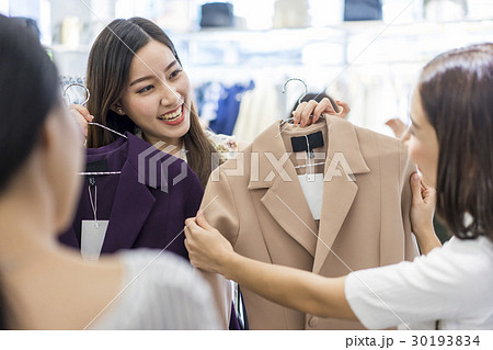 a woman is showing coat for her friends to choose. a woman is showing coat for her friends to choose. 30193834