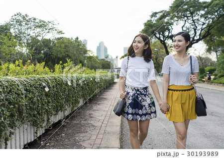 Both of women are hand in hand on the street. 30193989