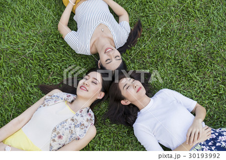 Dynamic ladies are relaxing on the grass. Dynamic ladies are relaxing on the grass. 30193992