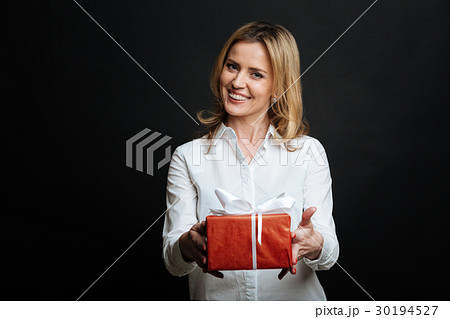 Smiling young woman presenting gift box in the Smiling young woman presenting gift box in the 30194527