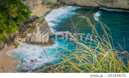 Rock in the ocean with beautiful palms behind at 30194670