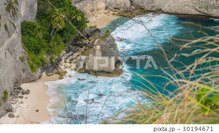 Rock in the ocean with beautiful palms behind at 30194671