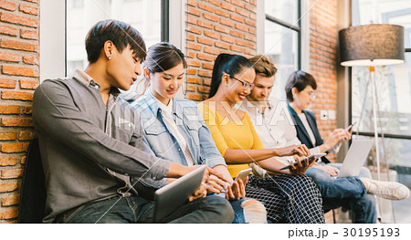 Multiethnic group using IT gadget devices together 30195193