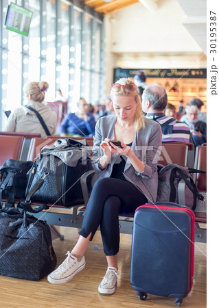 Female traveler using cell phone while waiting on 30195387