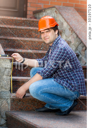Smiling male worker measuring stone staircase 30197510