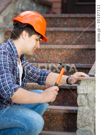 Young worker in helmet repairing stone staircase Young worker in helmet repairing stone staircase 30197511