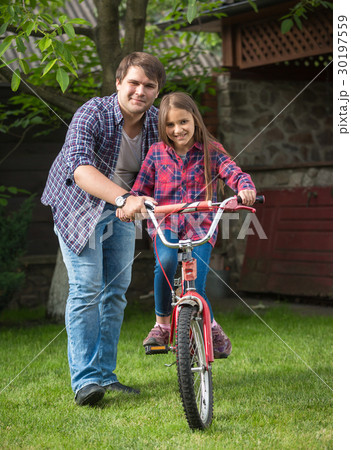 Young father teaching daughter how to ride bicycle 30197559
