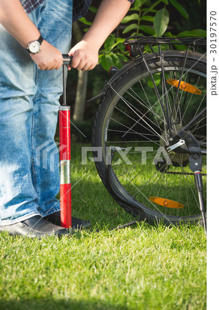 Closeup of young man pumping bicycle wheel 30197570