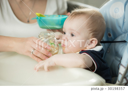 Closeup of mother feeding baby boy with porridge Closeup of mother feeding baby boy with porridge 30198357