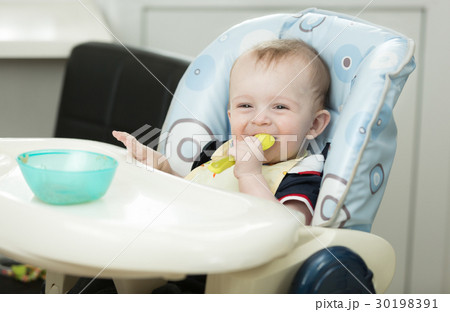 Portrait of smiling baby boy eating with spoon Portrait of smiling baby boy eating with spoon 30198391