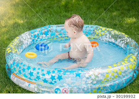 Boy playing with toys in swimming pool at garden Boy playing with toys in swimming pool at garden 30199932