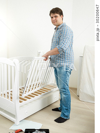 Young man assembling furniture in baby's room Young man assembling furniture in baby's room 30200647