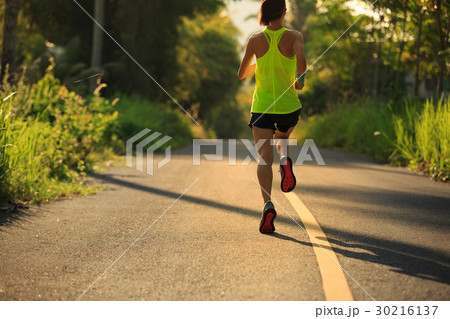 Young woman running on tropical forest trail 30216137
