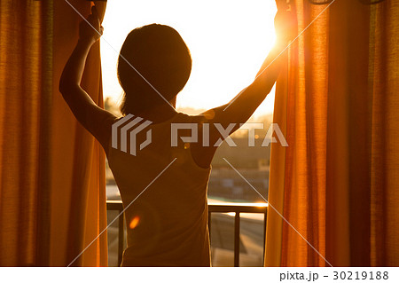 woman stand in the room open curtain see sunrise 30219188