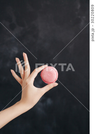Pink macaroon almond cake in a woman's hand Pink macaroon almond cake in a woman's hand 30220809