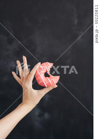 Pink donut in a woman's hand on black background Pink donut in a woman's hand on black background 30220811