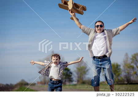 Father and son playing with cardboard toy airplane in the park a 30222525