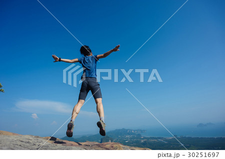 jumping on rocky mountain peak  30251697