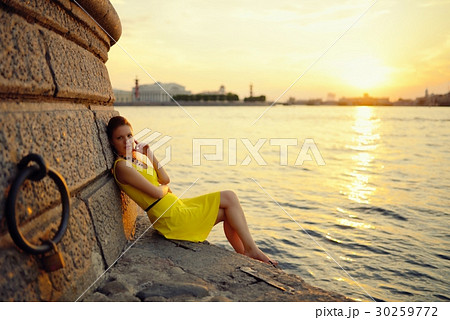 Portrait of the beautiful woman in a yellow dress on the embankment in Sankt Petersburg at sunset Portrait of the beautiful woman in a yellow dress on the embankment in Sankt Petersburg at sunset 30259772