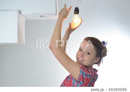 Young beautiful woman twists a bulb Young beautiful woman twists a bulb 30260090