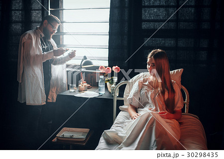 Male doctor with syringe against sick woman in bed 30298435