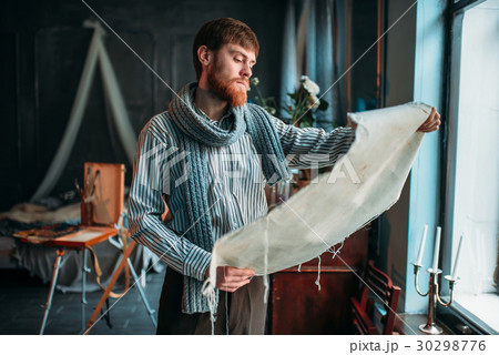 Painter looking at canvas painting against window Painter looking at canvas painting against window 30298776