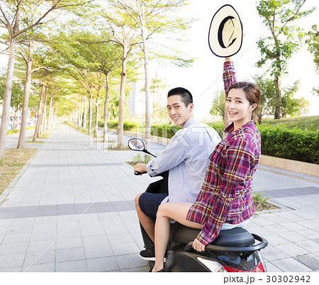 happy young couple riding scooter in town happy young couple riding scooter in town 30302942