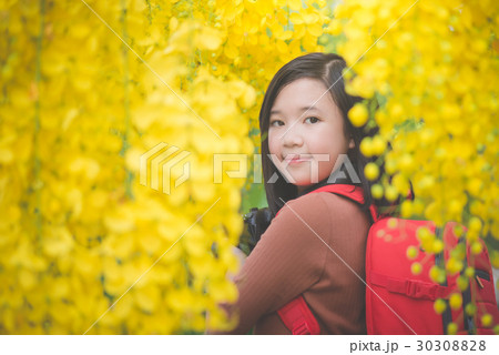 Asian girl take photo with blooming yellow flower 30308828