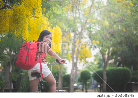 Beautiful Asian girl with red backpack riding bicy Beautiful Asian girl with red backpack riding bicy 30308848
