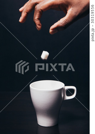 Hand of black man drop piece of sugar in white cup 30319556