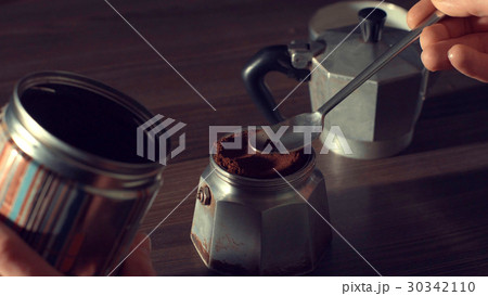 Man's hand pouring coffee in a geyser 30342110
