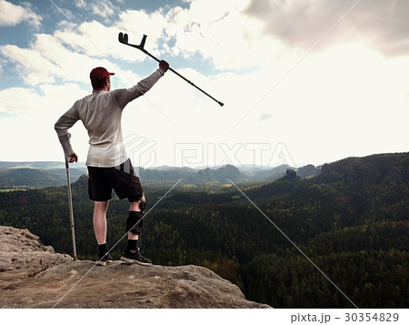 Man with leg in join immobilizer stay on summit 30354829
