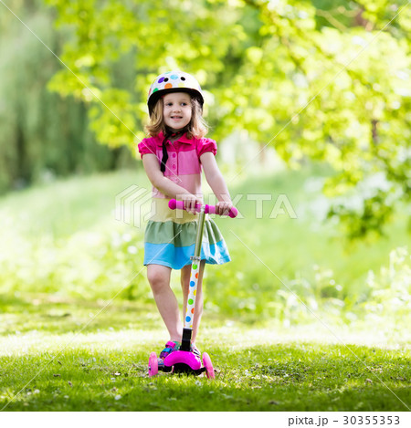 Little girl riding a colorful scooter 30355353