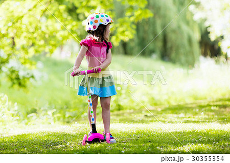 Little girl riding a colorful scooter 30355354