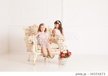 Two girls sits in a magnificent ancient armchair  30355673