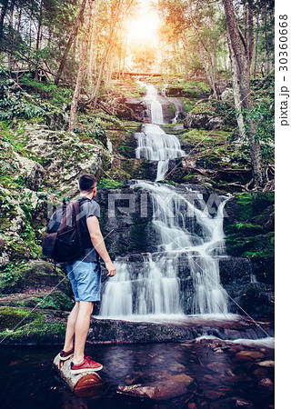 Tourist man standing near waterfall in the mountai 30360668