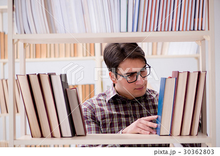 Young student looking for books in college library 30362803