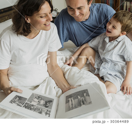 Family Looking Photobook Together at the Bedroom 30364489