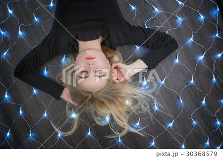 Female lying on garland with eyes closed 30368579