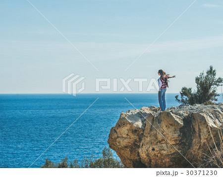 Young happy girl traveler standing on rock over Young happy girl traveler standing on rock over 30371230