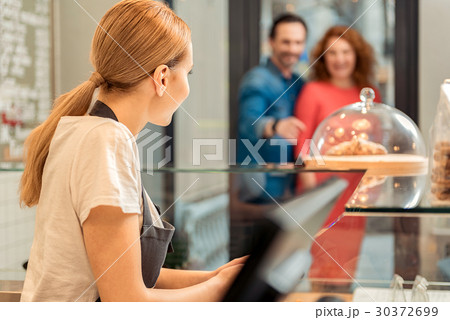 Positive saleswoman meeting clients in sweet-shop Positive saleswoman meeting clients in sweet-shop 30372699